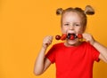 Baby girl kid in red t-shirt holding smelling biting eating fresh berries cherry strawberry raspberry on skewer Royalty Free Stock Photo