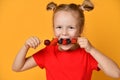 Baby girl kid in red t-shirt holding smelling biting eating fresh berries dessert with cherry strawberry raspberry on skewer Royalty Free Stock Photo