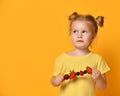 Baby girl kid in t-shirt holding smelling biting eating fresh berries cherry strawberry raspberry on skewer Royalty Free Stock Photo