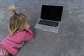 Baby girl laying at gray rug and watching at laptop, Royalty Free Stock Photo