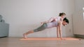 Baby girl lies on her mother`s back who does plank exercise on yoga mat at home Royalty Free Stock Photo