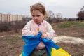 A baby girl with little sister with a flag of Ukraine against the backdrop of a city and a lake in a Ukrainian city