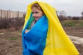 A baby girl with little sister with a flag of Ukraine against the backdrop of a city and a lake in a Ukrainian city