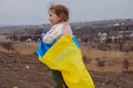 A baby girl with little sister with a flag of Ukraine against the backdrop of a city and a lake in a Ukrainian city