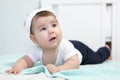 Baby girl lying on bed with white bandage on her head, Caucasian infant portrait