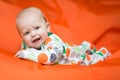 Baby girl lying on a belly on an orange pillow Royalty Free Stock Photo