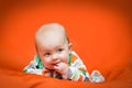 Baby girl lying on a belly on an orange pillow Royalty Free Stock Photo