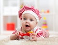 Baby girl lying on the floor and plays with toy indoor Royalty Free Stock Photo