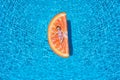 Baby girl is lying on a orange slice shaped float over blue pool water Royalty Free Stock Photo