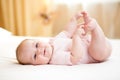 Baby girl lying on white sheet and holding her feet Royalty Free Stock Photo