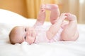 Baby girl lying on white sheet and holding legs Royalty Free Stock Photo