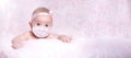 The baby girl is in a medical mask with a bow on her head. Concept pandemic coronavirus Covid 19