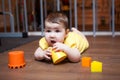 Baby girl 7 months old chewing on teething toy, while lying on hardwood floor Royalty Free Stock Photo