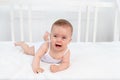 Baby girl 6 months old lying on the bed in the children`s room on her stomach and crying, baby morning, baby products concept Royalty Free Stock Photo