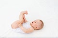 Baby girl 6 months old lying on the bed in the nursery on her back and holding her legs, baby morning, baby products concept Royalty Free Stock Photo