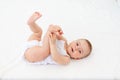 Baby girl 6 months old lying in a crib in the children`s room on her back and holding her legs, looking at the camera, baby`s Royalty Free Stock Photo