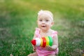 Baby girl 10 months old sitting on the grass in the summer and playing pyramid, early development of children, outdoor games Royalty Free Stock Photo