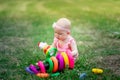 Baby girl 10 months old sitting on the grass in the summer and playing pyramid, early development of children, outdoor games Royalty Free Stock Photo