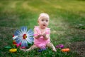 Baby girl 10 months old sitting on the grass in the summer and playing with a turntable, early development of children, outdoor Royalty Free Stock Photo