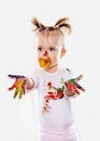 The baby girl with a pacifier in gouache soiled hands and shirt isolated