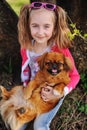 Baby girl with a pekinese sitting on the grass