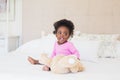 Baby girl in pink babygro sitting on bed Royalty Free Stock Photo