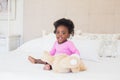 Baby girl in pink babygro sitting on bed Royalty Free Stock Photo