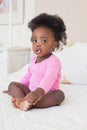 Baby girl in pink babygro sitting on bed Royalty Free Stock Photo