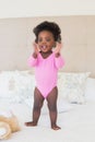 Baby girl in pink babygro standing on bed Royalty Free Stock Photo