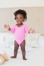 Baby girl in pink babygro standing on bed Royalty Free Stock Photo