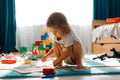 Baby girl playing indoors sitting on floor in playroom at home with constructor. Educational game for baby and toddler Royalty Free Stock Photo