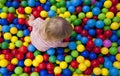 Baby girl playing in playground colourful ball pool. Closup overview