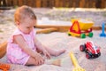 Baby girl playing in sandbox on outdoor playground. Child with colorful sand toys. Healthy active baby outdoors plays games Royalty Free Stock Photo