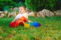 Baby girl playing with a waldorf material, a rainbow of wood montessori, in nature