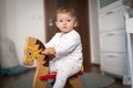 Baby girl playing on wooden rocking horse. Childhood, game at home concept