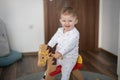 Happy baby girl playing on wooden rocking horse. Childhood, game at home concept Royalty Free Stock Photo