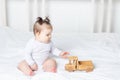 Baby girl playing wooden toy typewriter on the bed at home, the concept of play and development of children Royalty Free Stock Photo