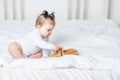 Baby girl playing wooden toy typewriter on the bed at home, the concept of play and development of children Royalty Free Stock Photo