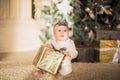Baby girl posing with a gift sitting on a floor against Christmas back. Royalty Free Stock Photo