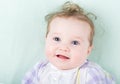 Baby girl in a purple dress lying on a green knitted blanket Royalty Free Stock Photo