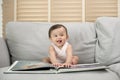 Baby girl reading a book sitting on sofa at home Royalty Free Stock Photo