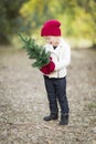 Baby Girl In Red Mittens and Cap Holding Small Christmas Tree Royalty Free Stock Photo