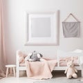 Baby girl room with empty mockup photoframe on light wall. Bed, toys, blanket. Frame with copy space for picture on wall