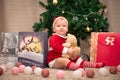 Baby girl in Santa Claus costume with gifts under the Christmas tree. Girl playing with toys Royalty Free Stock Photo