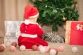 Baby girl in Santa Claus costume with gifts under the Christmas tree. Girl playing with toys Royalty Free Stock Photo
