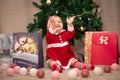 Baby girl in Santa Claus costume with gifts under the Christmas tree. Girl playing with toys Royalty Free Stock Photo