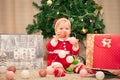 Baby girl in Santa Claus costume with gifts under the Christmas tree. Girl playing with toys Royalty Free Stock Photo