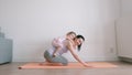 Baby girl sits on her mother`s back who exercises on yoga mat at home Royalty Free Stock Photo