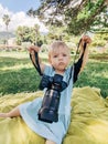 Budva, Montenegro - 10 june 2020: A baby girl sits in a park on a plaid, with a Sony a7iii camera and 35mm f1.4 Carl