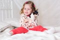 Baby girl is sitting on bed at home with dog Royalty Free Stock Photo